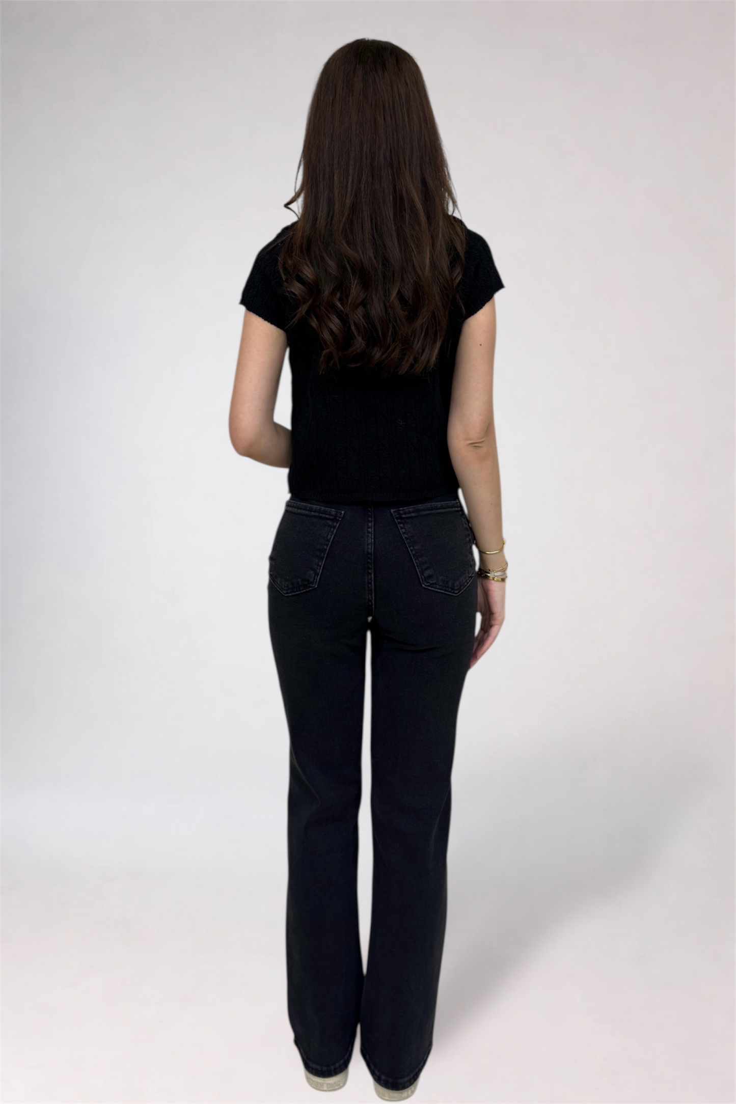 Person wearing black jeans and a black top on a white background