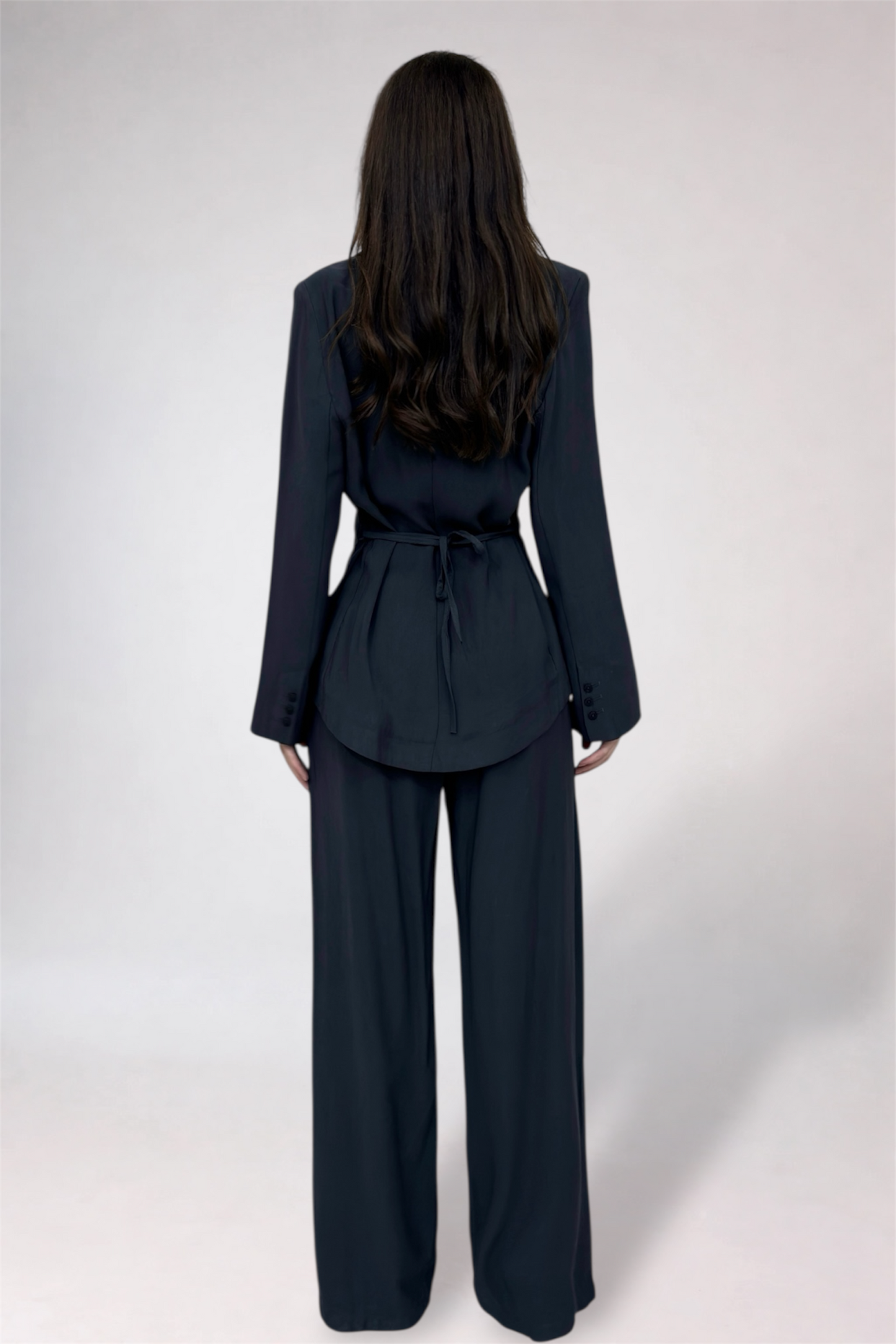 Person wearing a dark blue suit with wide-leg pants on a white background