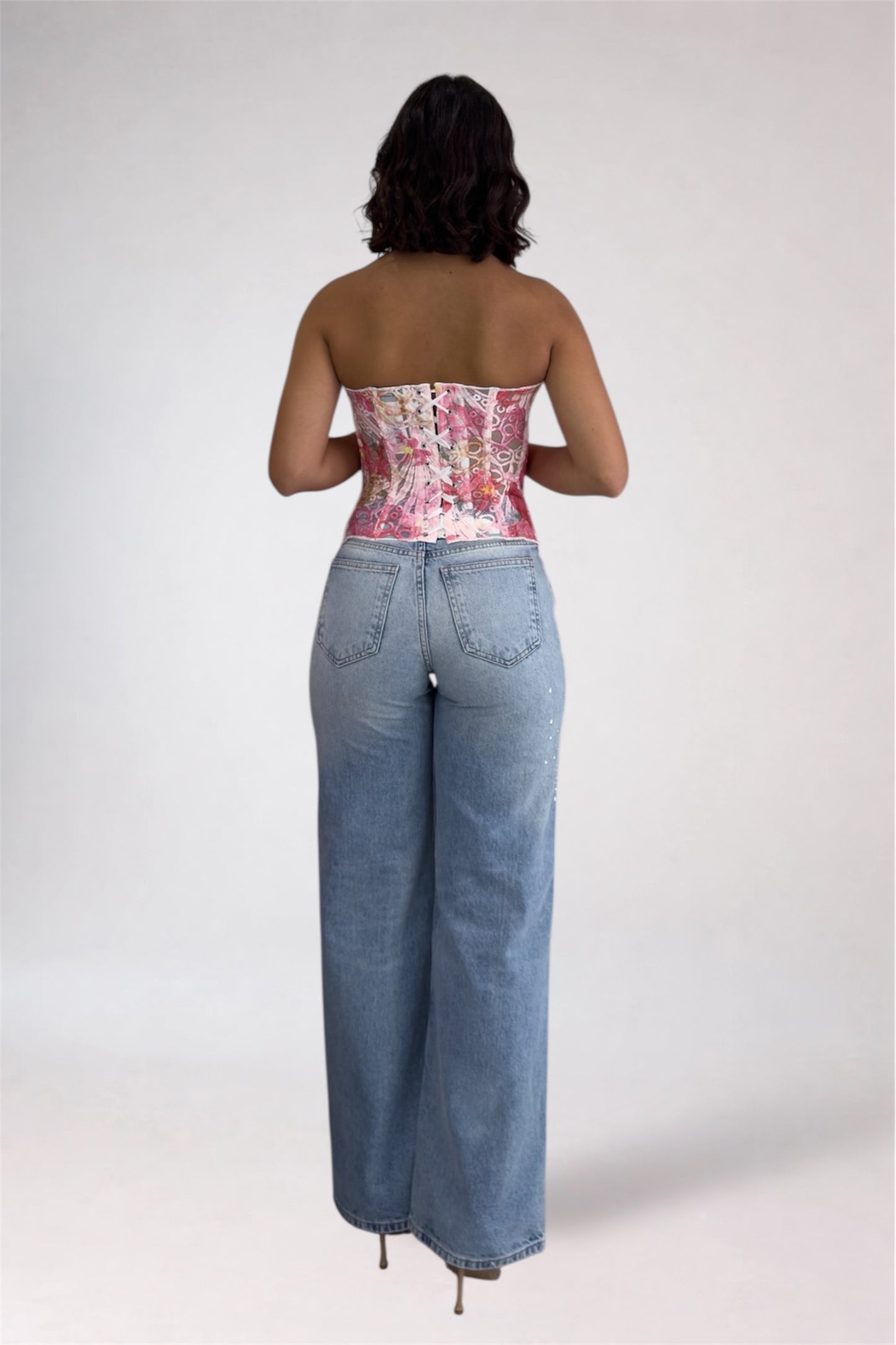 Person wearing a floral strapless top and blue jeans on a white background