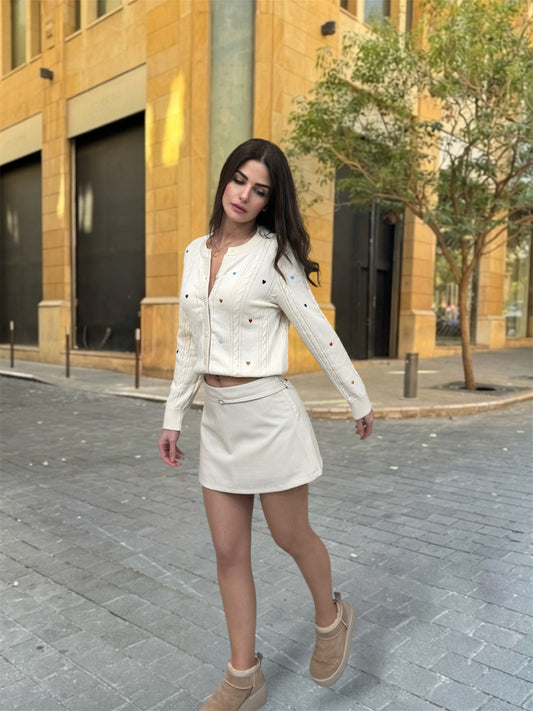 Woman in a white outfit walking on a street with buildings and trees in the background