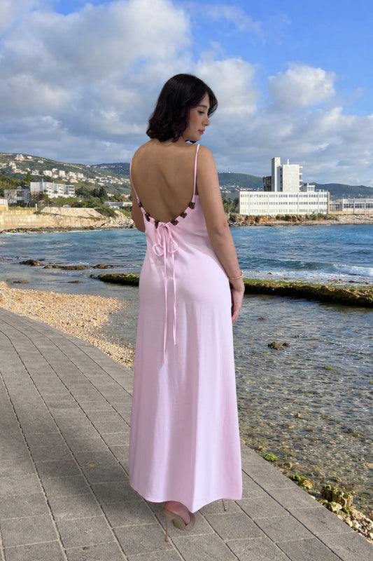 Woman in a pink dress standing by the sea with a scenic background