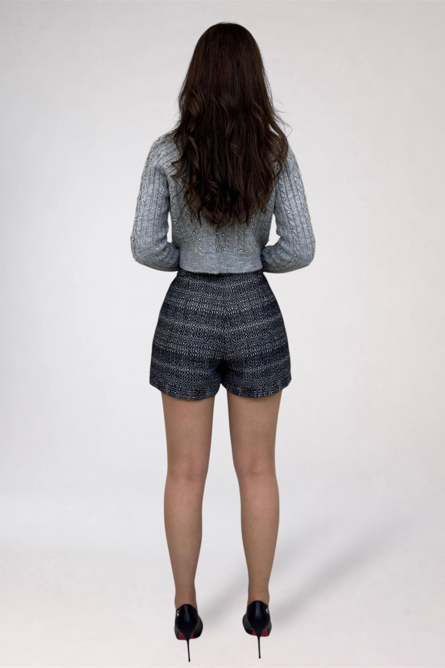 Person wearing a gray top and patterned shorts on a white background