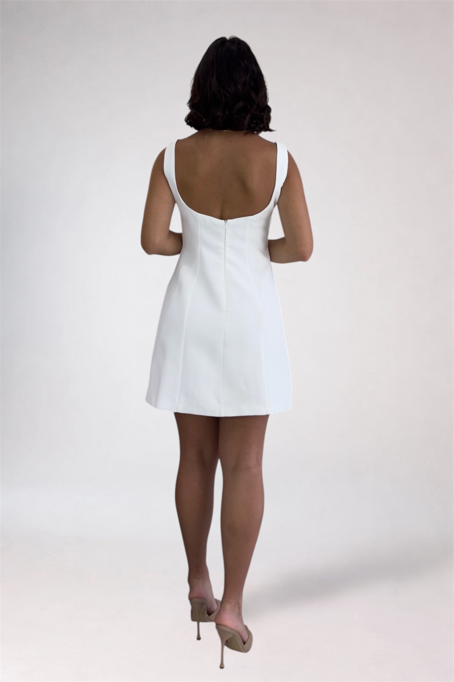 Person wearing a white dress on a plain background