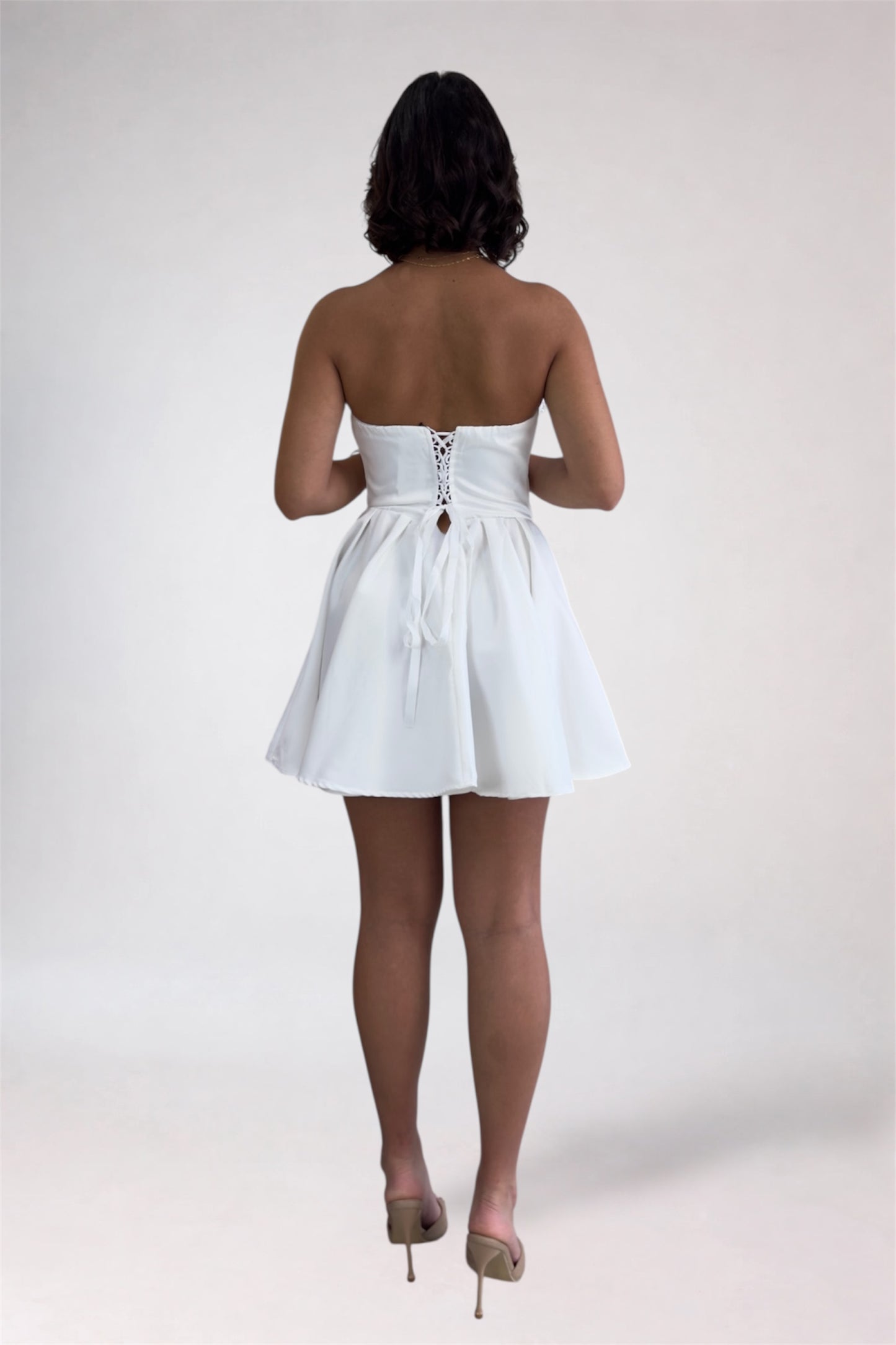 Woman wearing a white strapless dress on a plain background