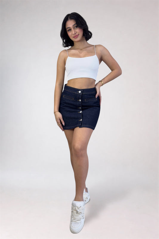 Woman wearing a white top and dark denim skirt on a plain background