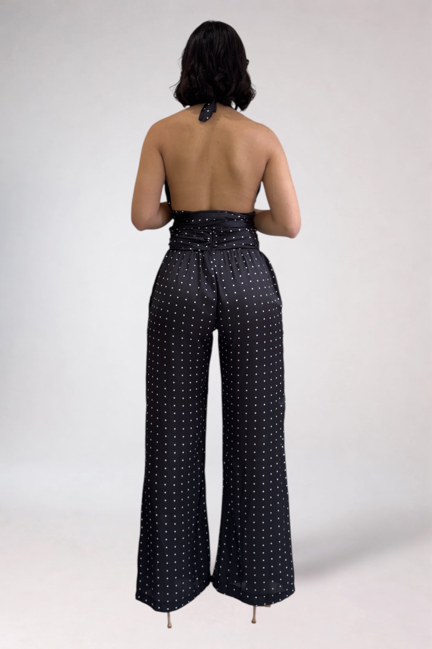 Person wearing a black polka dot jumpsuit on a white background