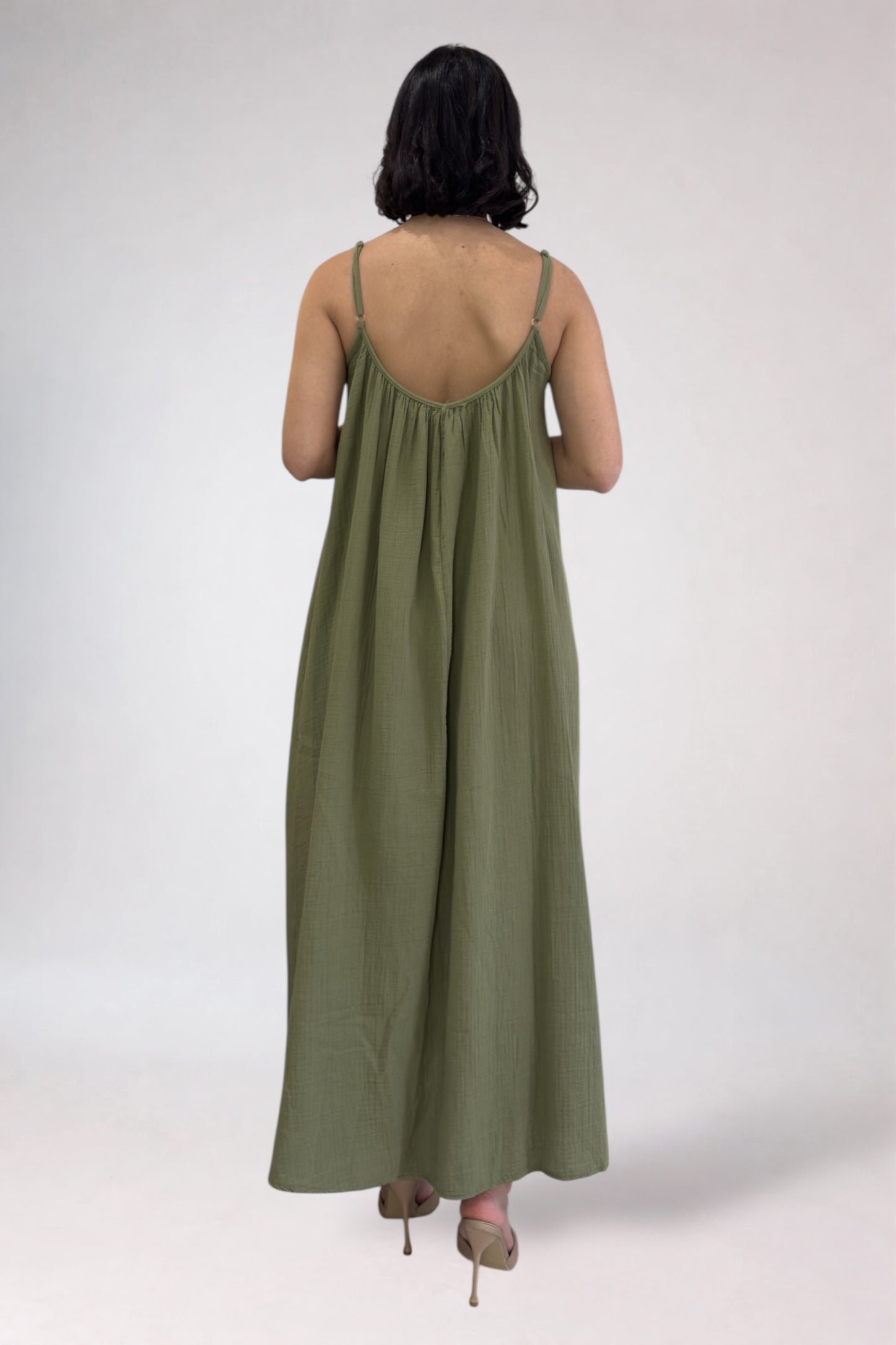 Person wearing a green dress with thin straps on a white background