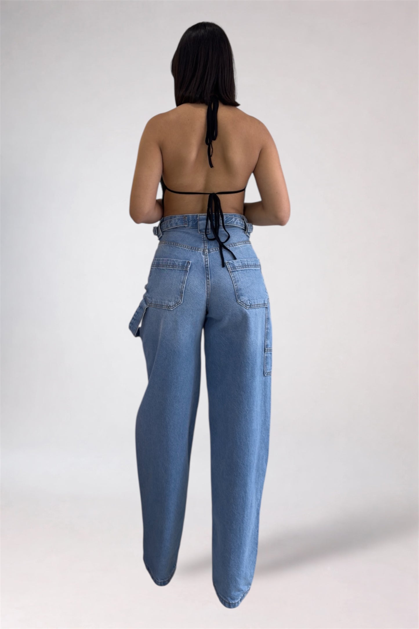 Person wearing high-waisted blue jeans and a black top on a white background