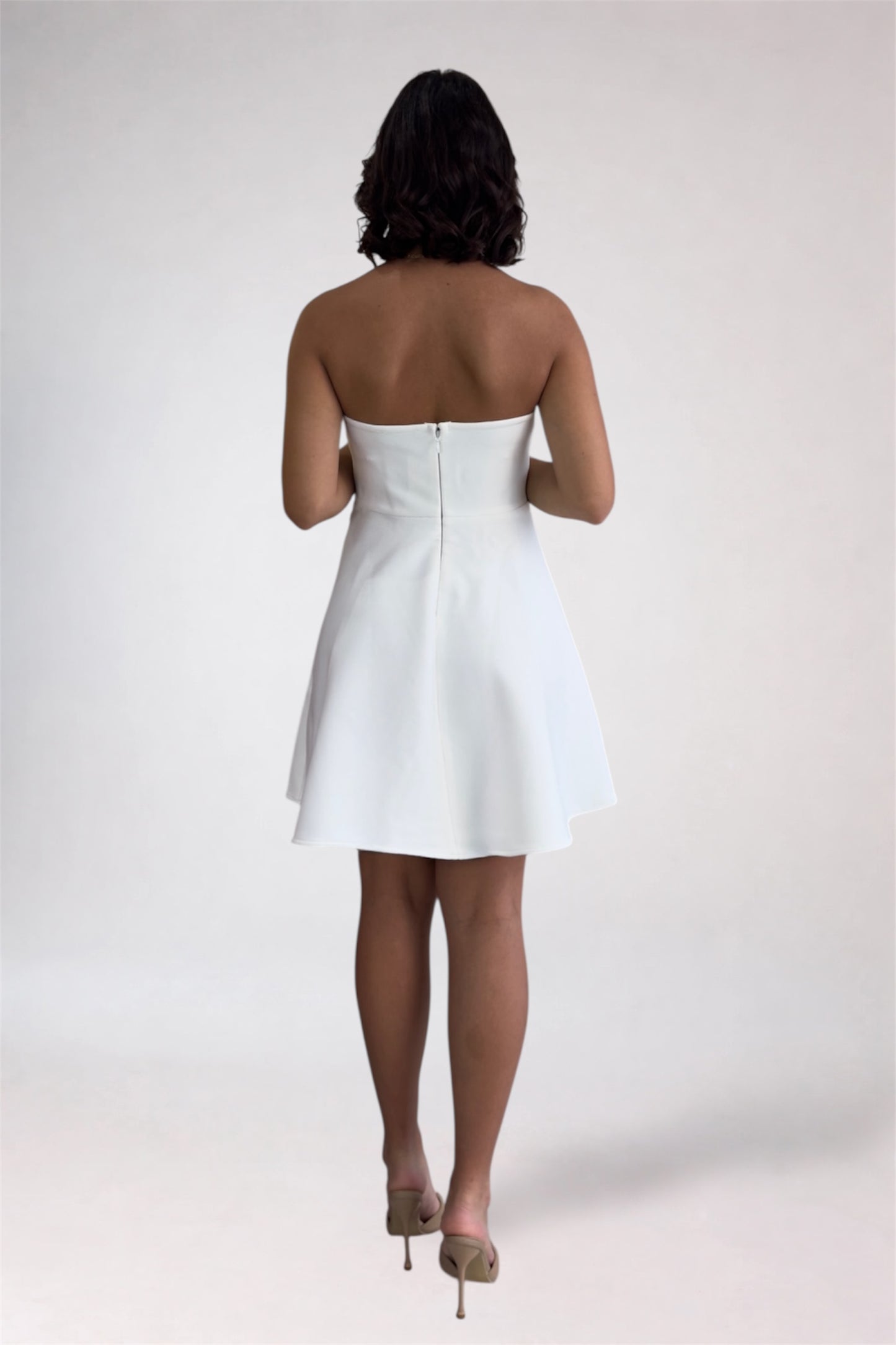 Person wearing a white strapless dress on a plain background