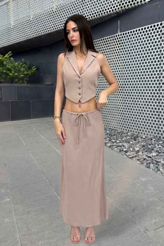 Woman in a beige outfit standing against a modern architectural background