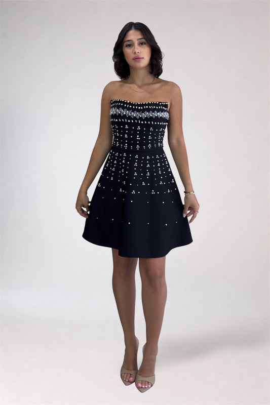 Woman wearing a strapless black dress with white pattern on a white background