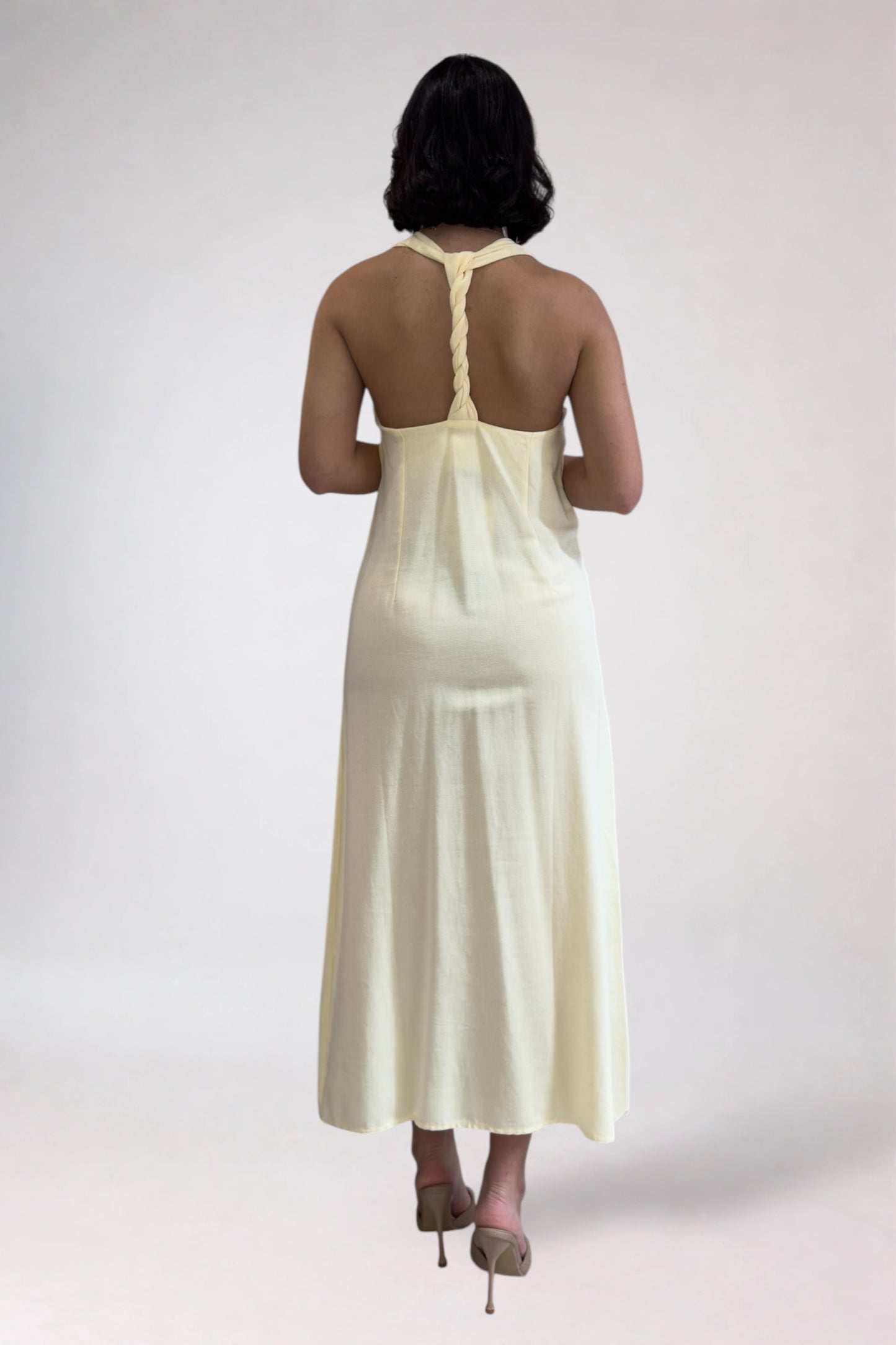 Woman wearing a light-colored dress with a plain background