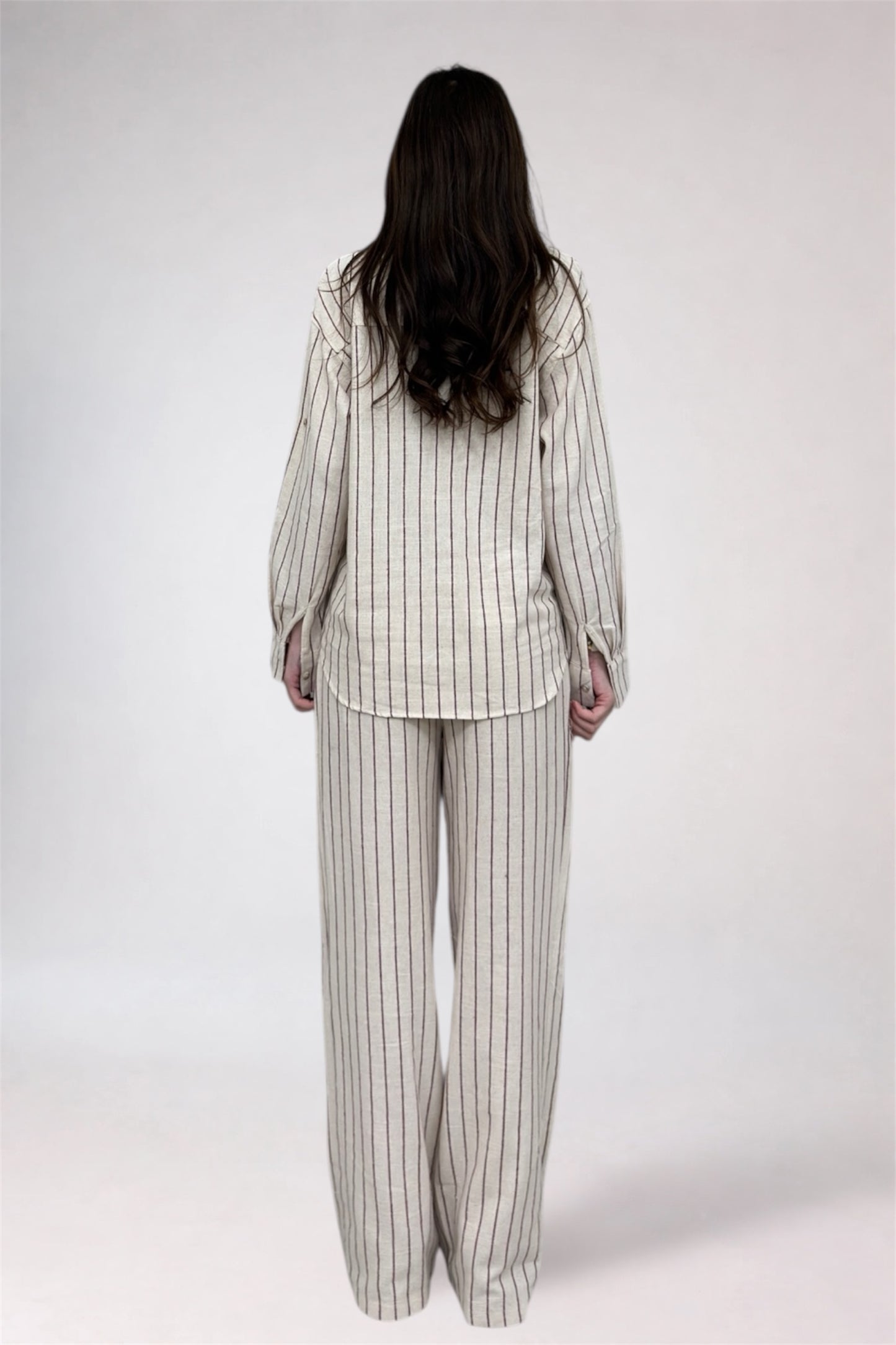 Person wearing a striped pajama set on a white background