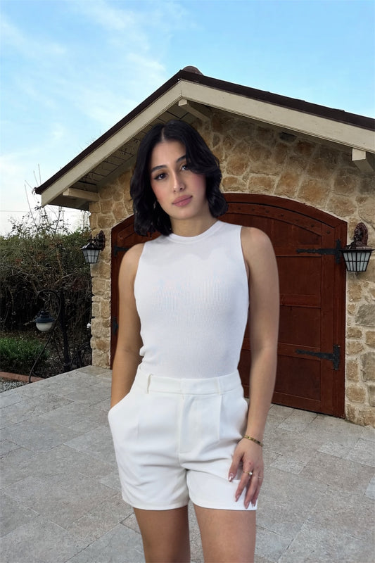 Woman in a white outfit standing in front of a stone building with a wooden door.