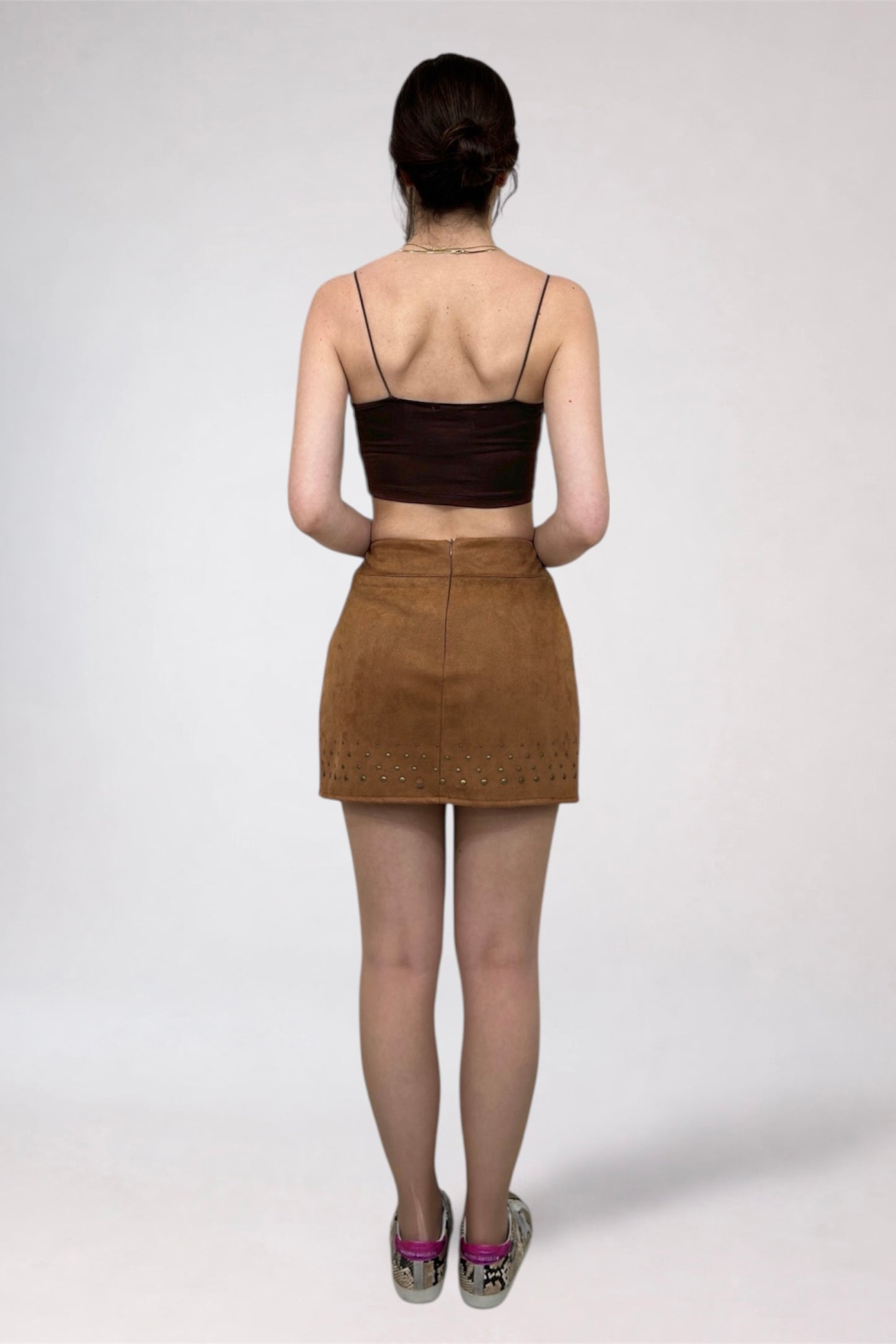 Person wearing a brown top and skirt on a white background