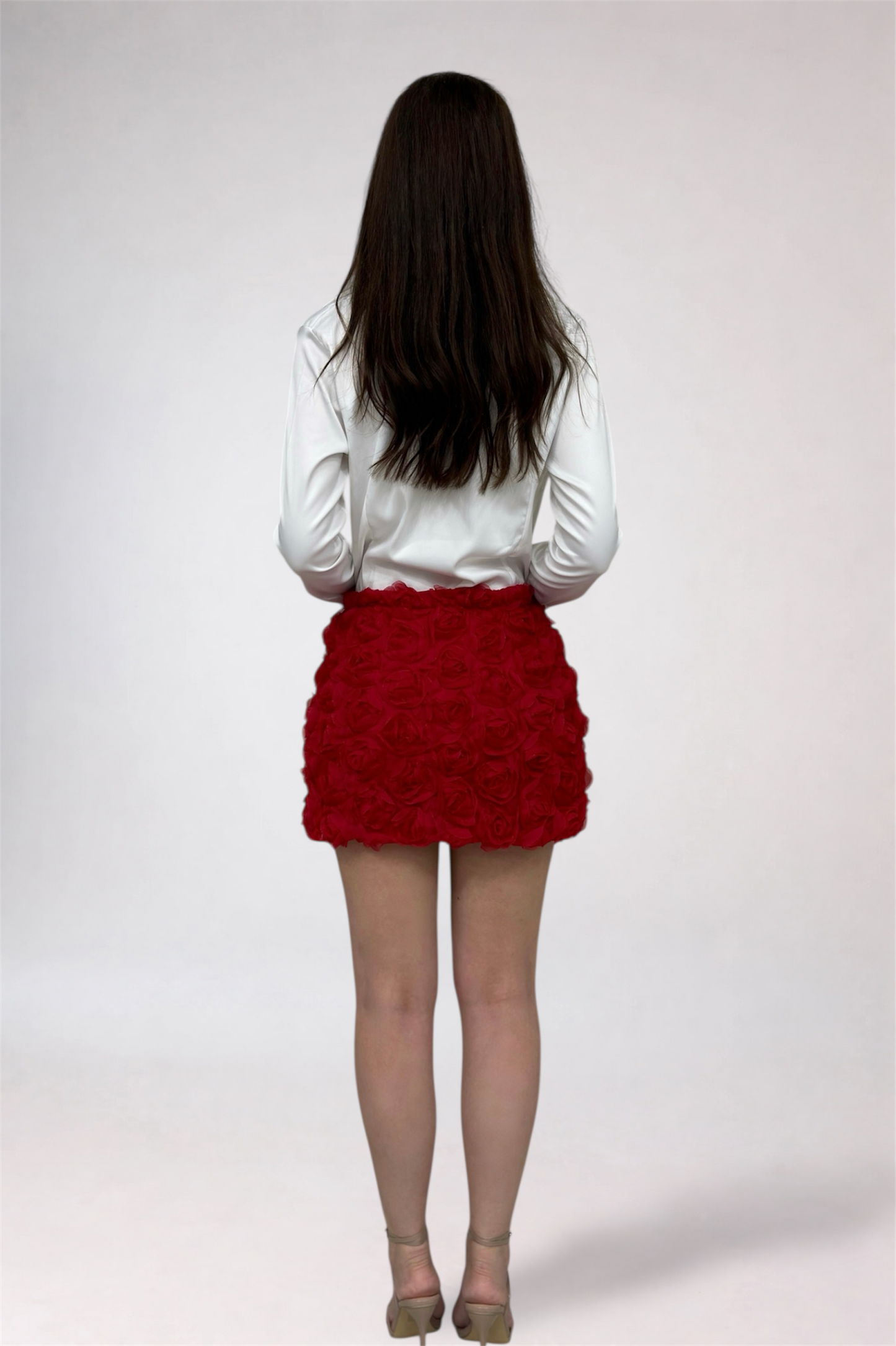 Person wearing a white blouse and red skirt on a plain background