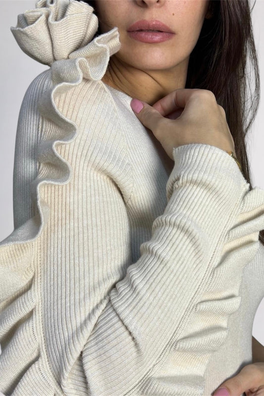 Close-up of a person wearing a cream-colored sweater with a textured design.