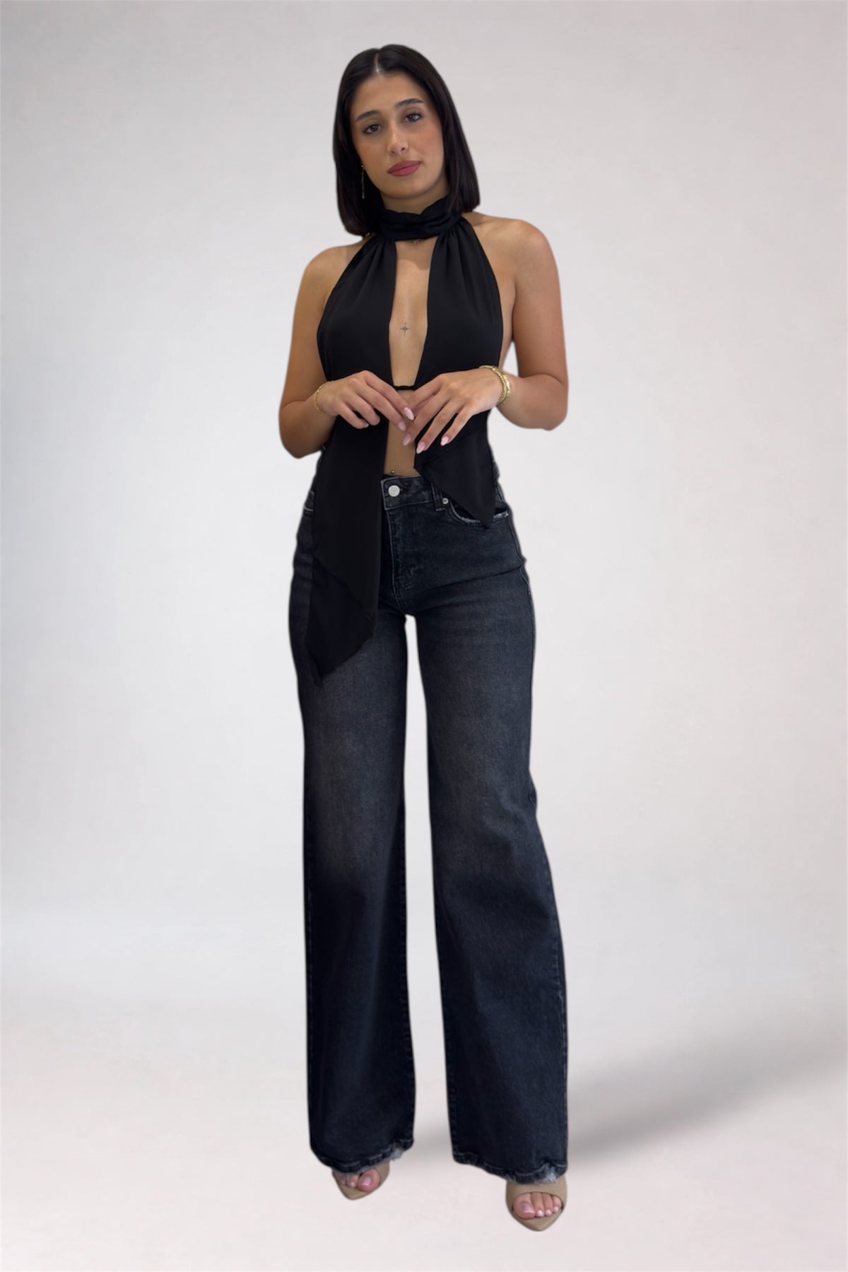 Woman wearing a black sleeveless top and dark blue jeans on a white background