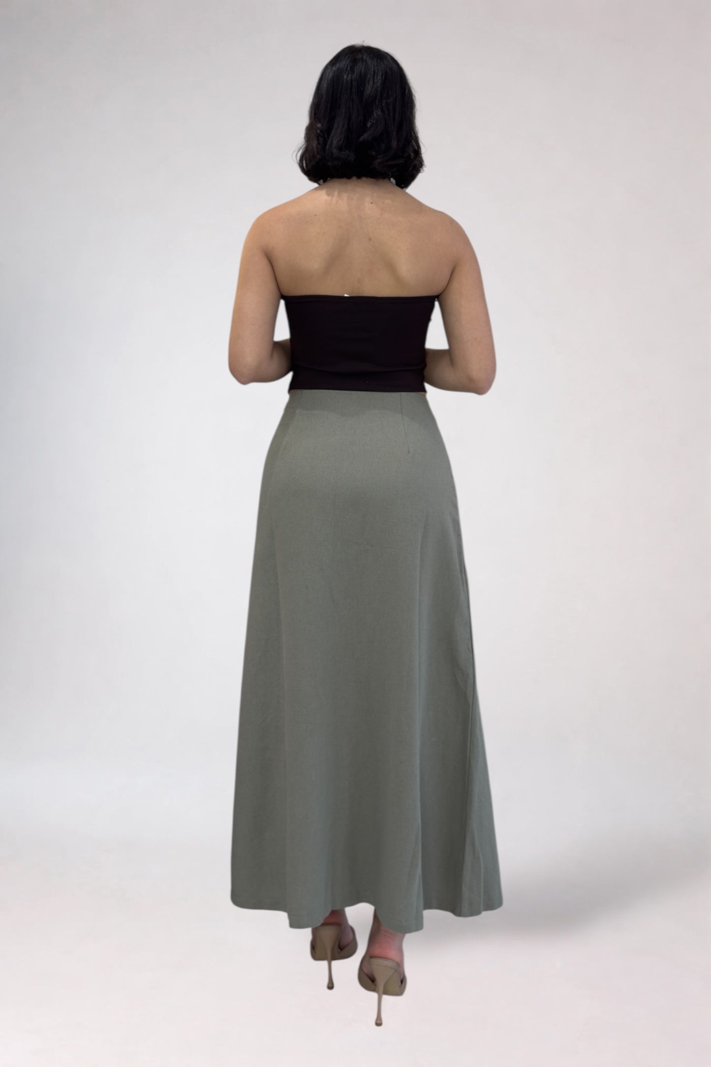 Woman wearing a black strapless top and long green skirt on a white background