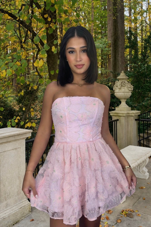 Woman wearing a light pink strapless dress in a garden setting