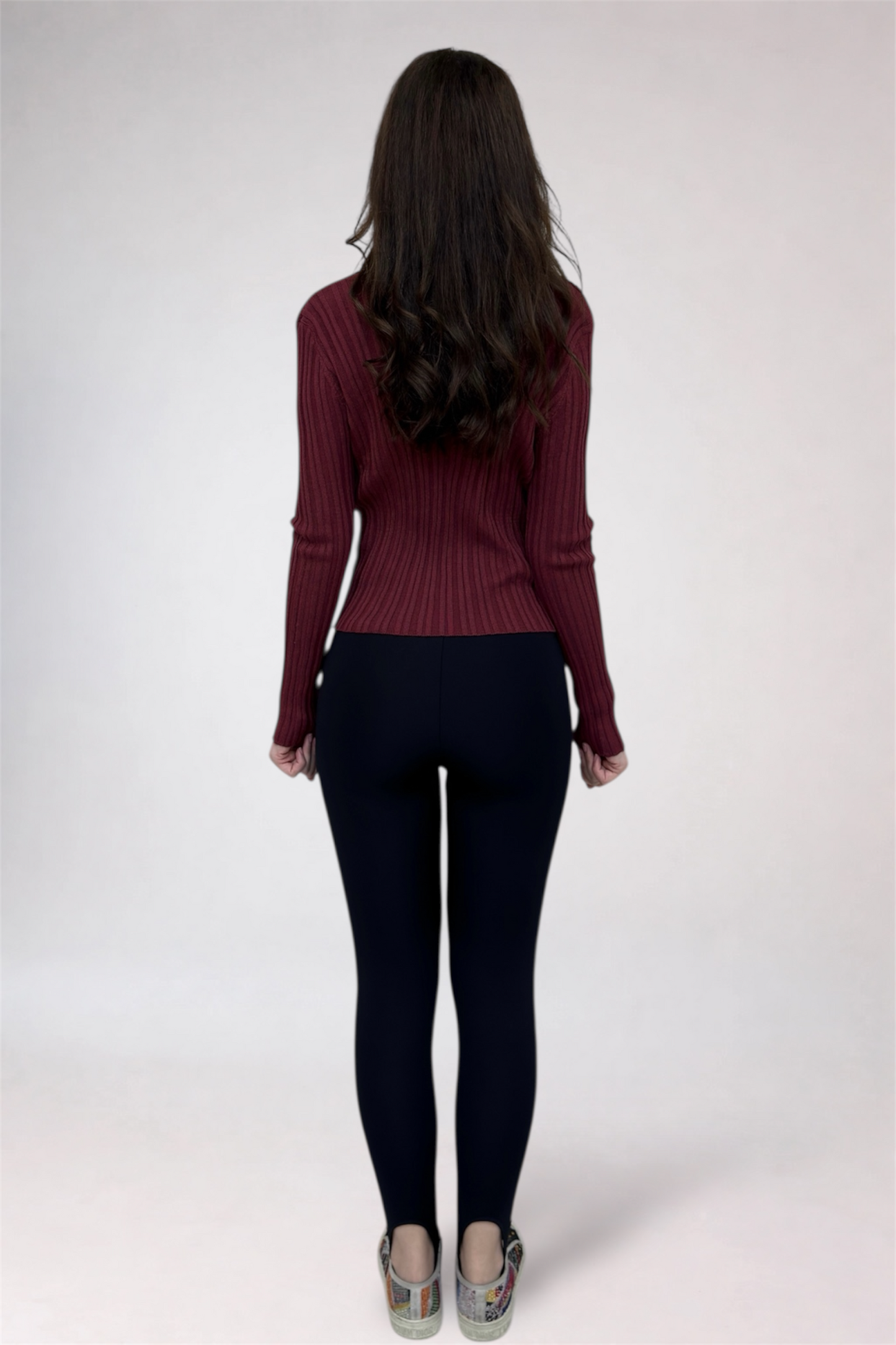 Person wearing a maroon sweater and black pants on a white background