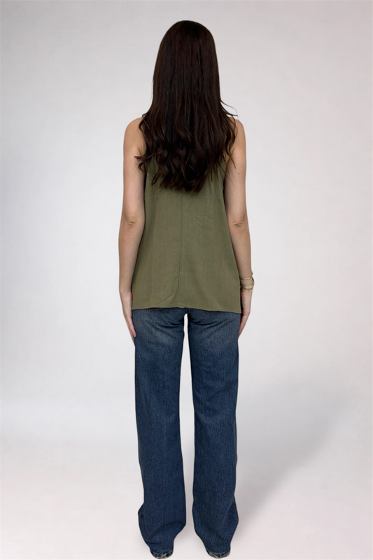 Person wearing a green sleeveless top and blue jeans on a white background