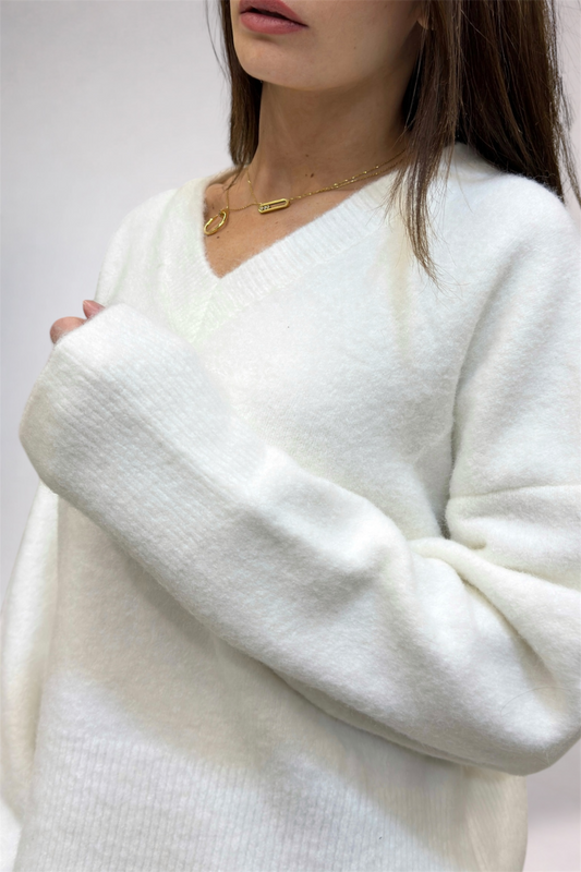 White sweater worn by a person with a plain background