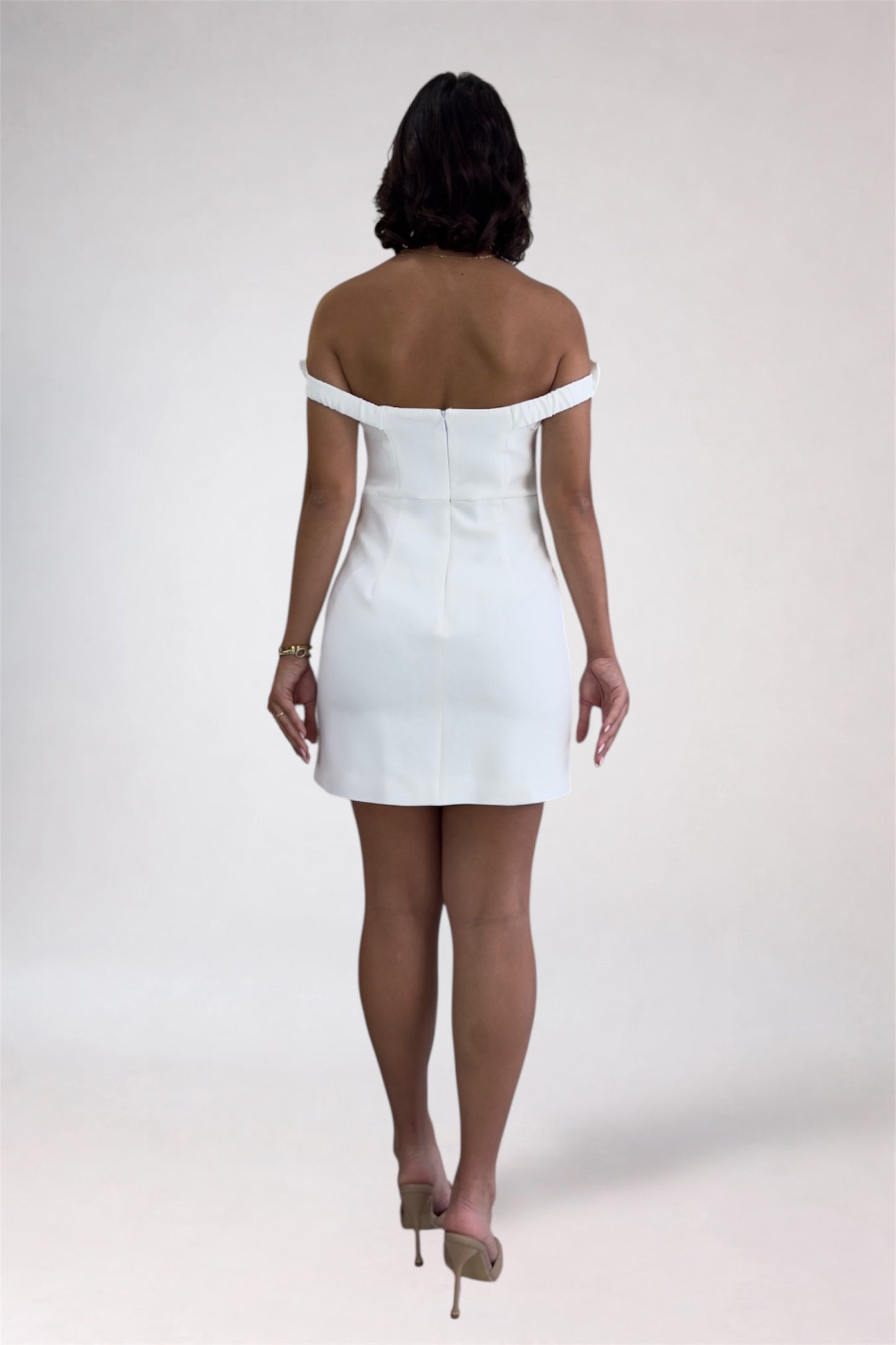 Person wearing a white off-shoulder dress on a plain background