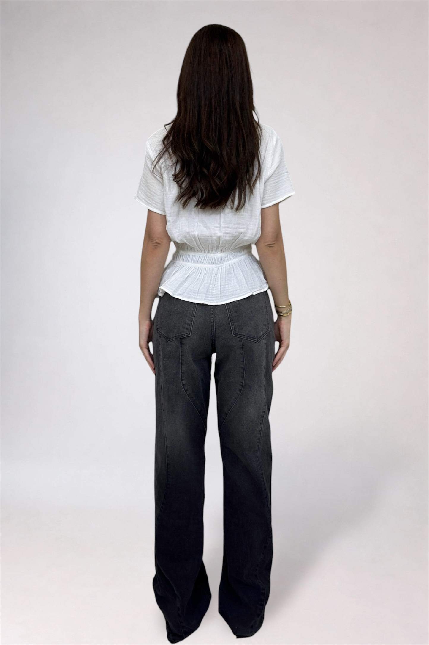 Person wearing a white top and dark pants on a white background