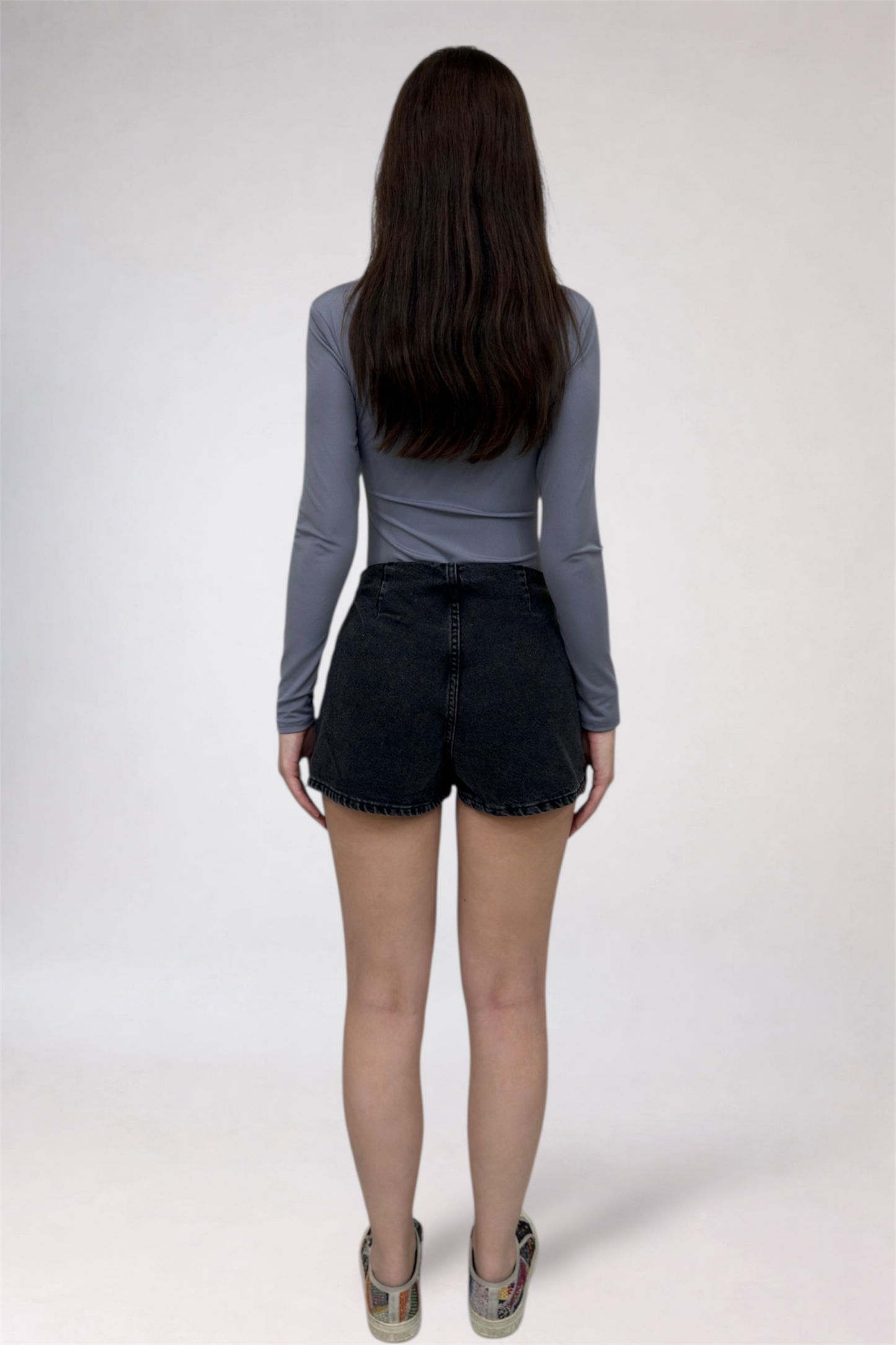 Person wearing a gray long-sleeve top and black shorts on a white background