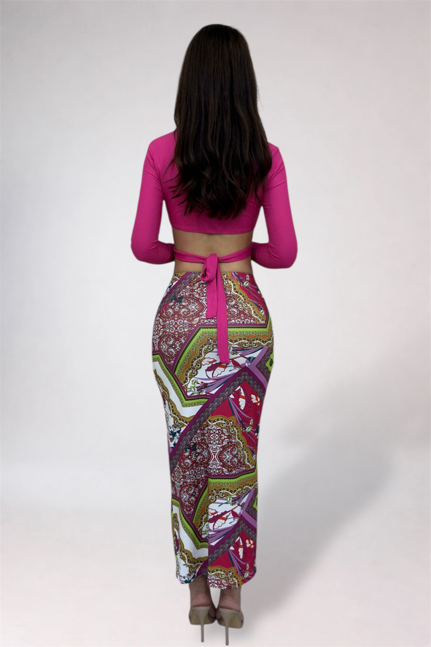 Woman wearing a pink top and patterned skirt on a white background