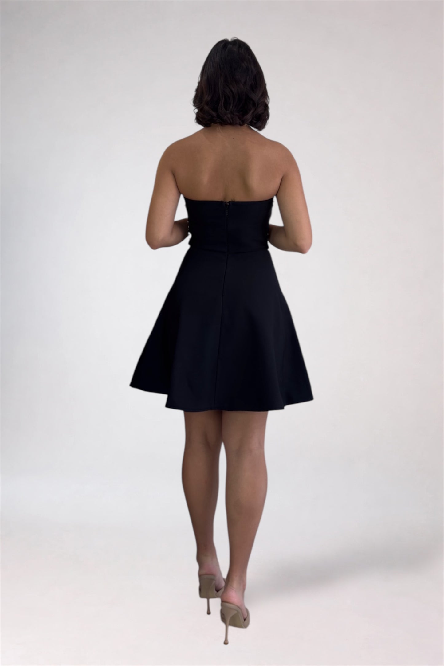 Woman wearing a black strapless dress on a white background