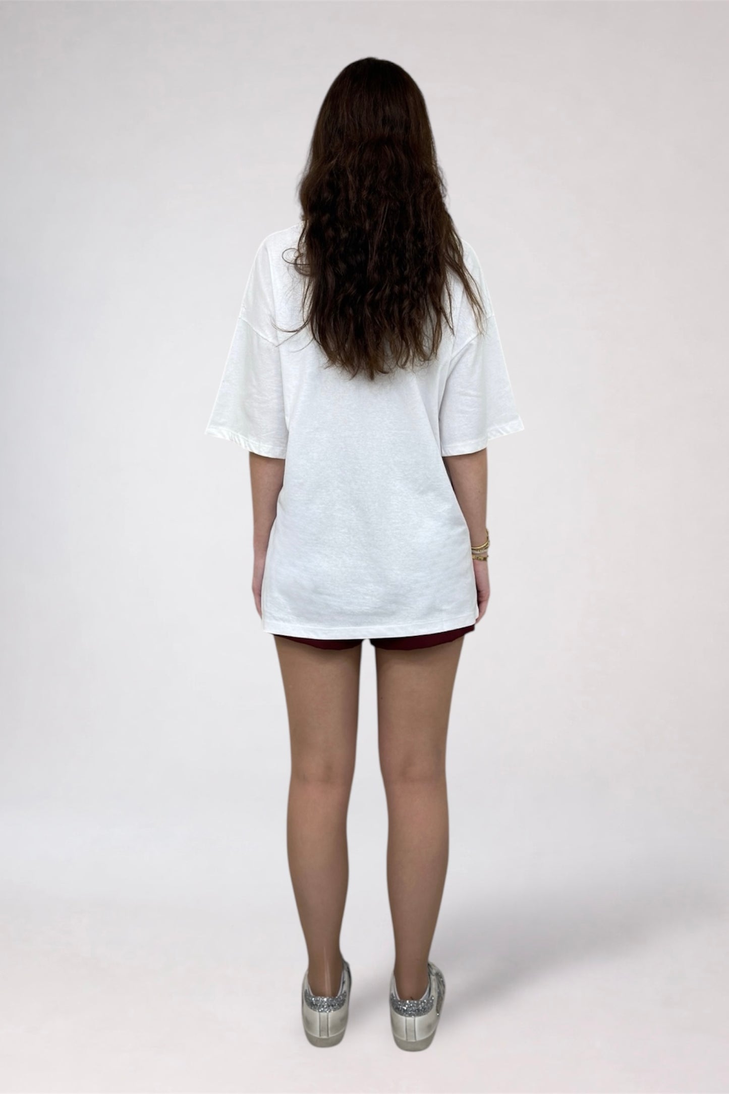 Person wearing a white tunic over a black skirt on a plain background
