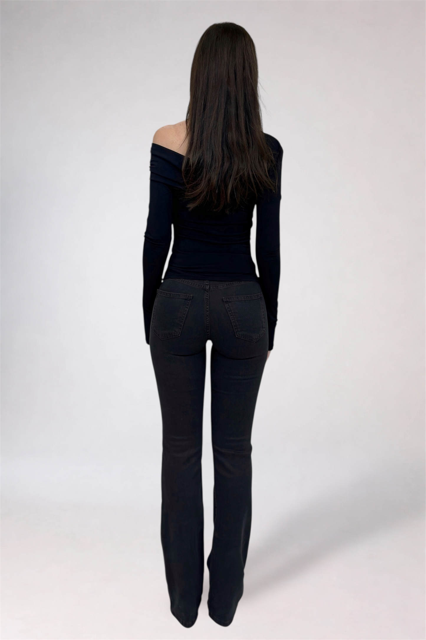 Woman wearing a black off-shoulder top and black pants on a white background