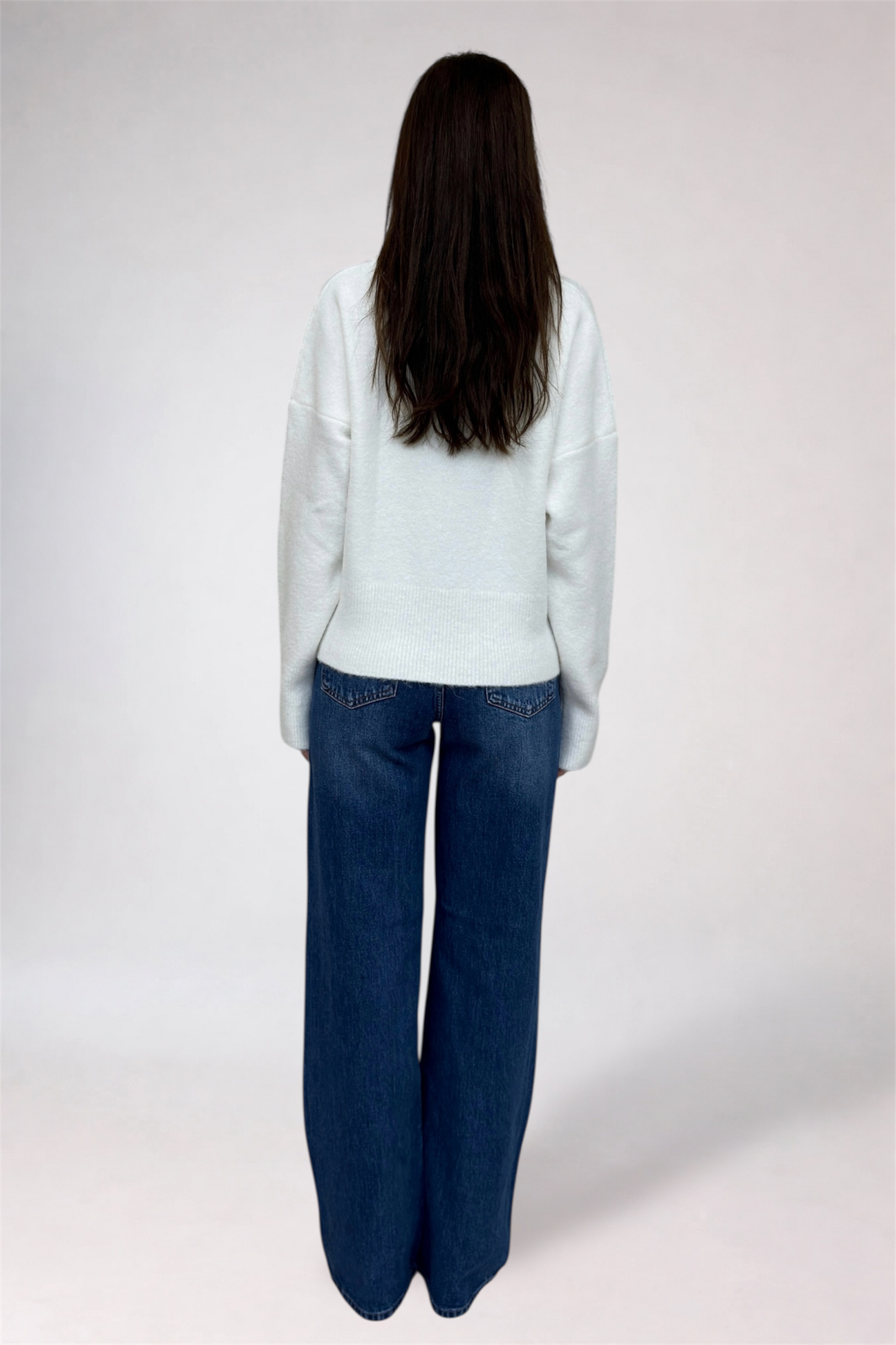 Person wearing a light blue blazer and dark blue jeans on a white background