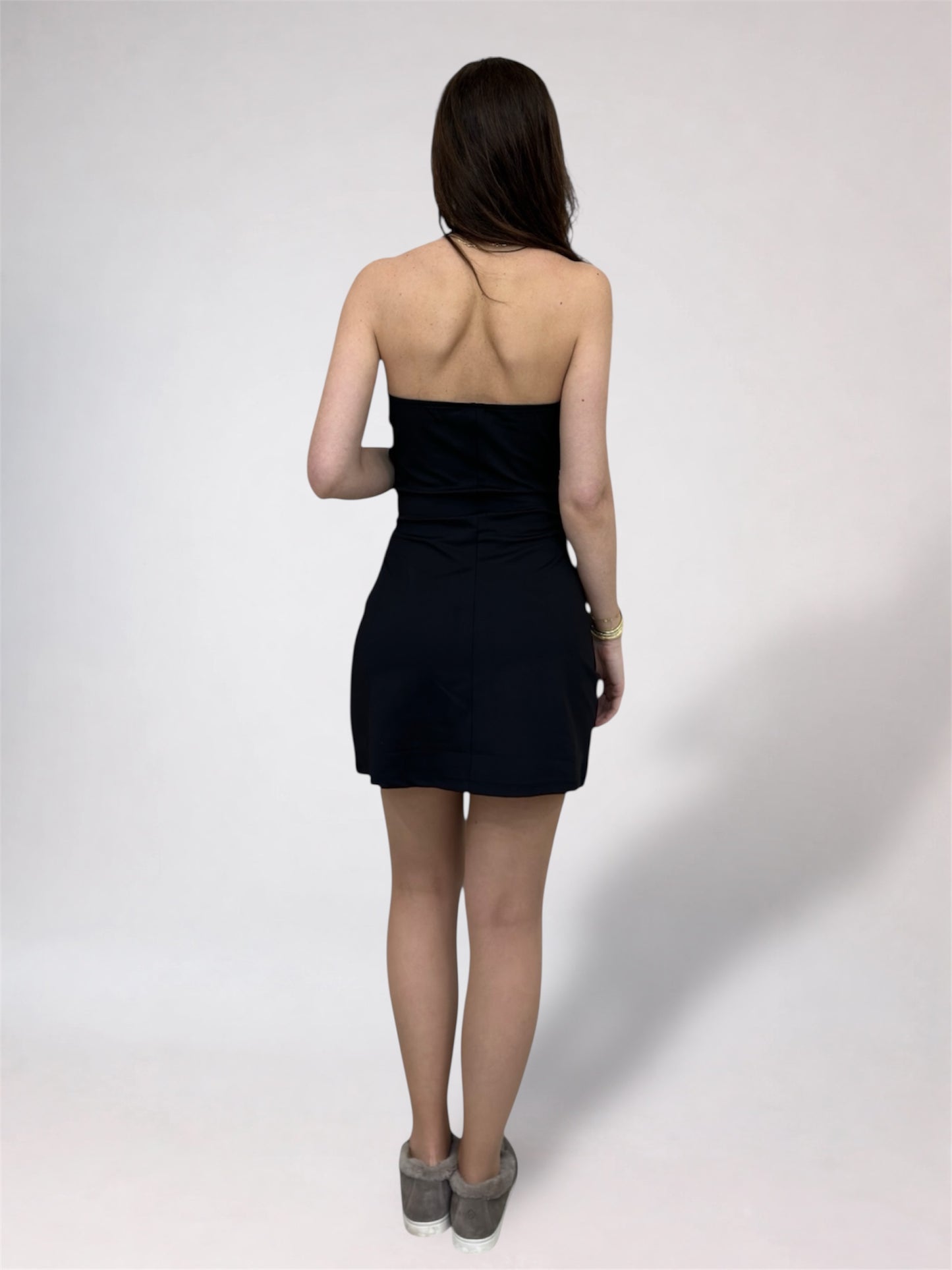 Woman wearing a black dress from behind on a white background