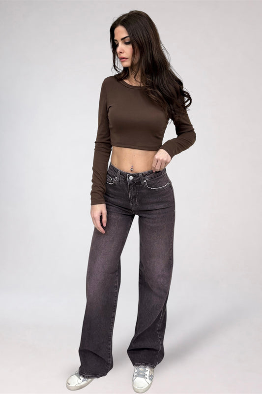 Woman wearing a brown long-sleeve top and dark jeans on a white background