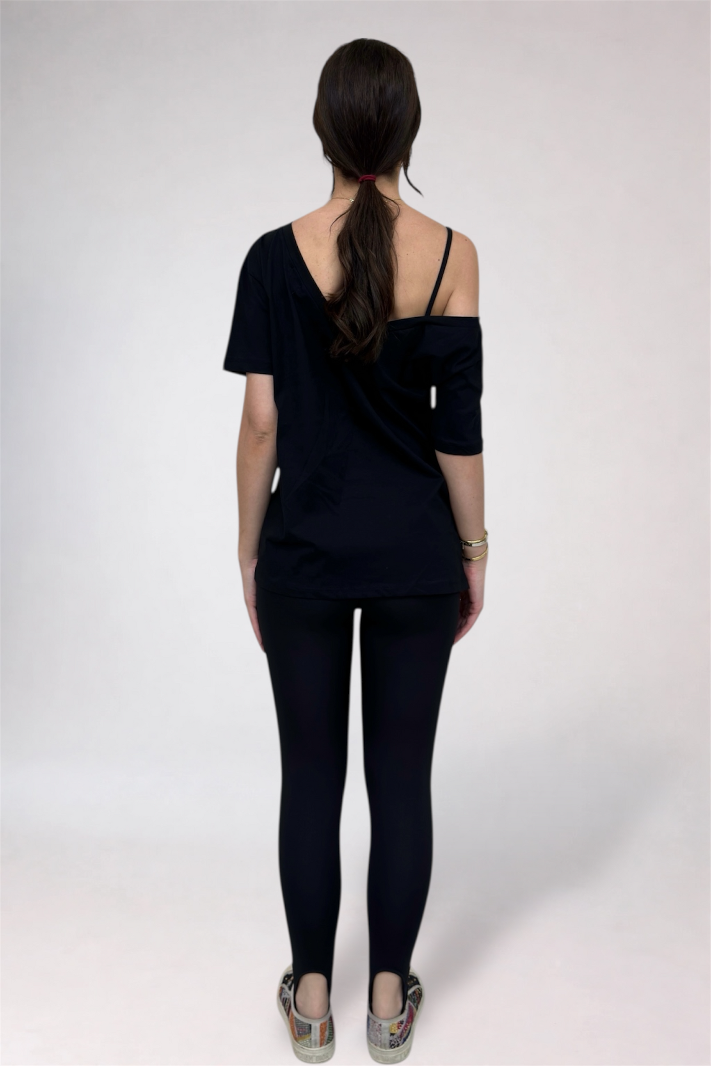 Person wearing a black off-shoulder top and leggings on a white background