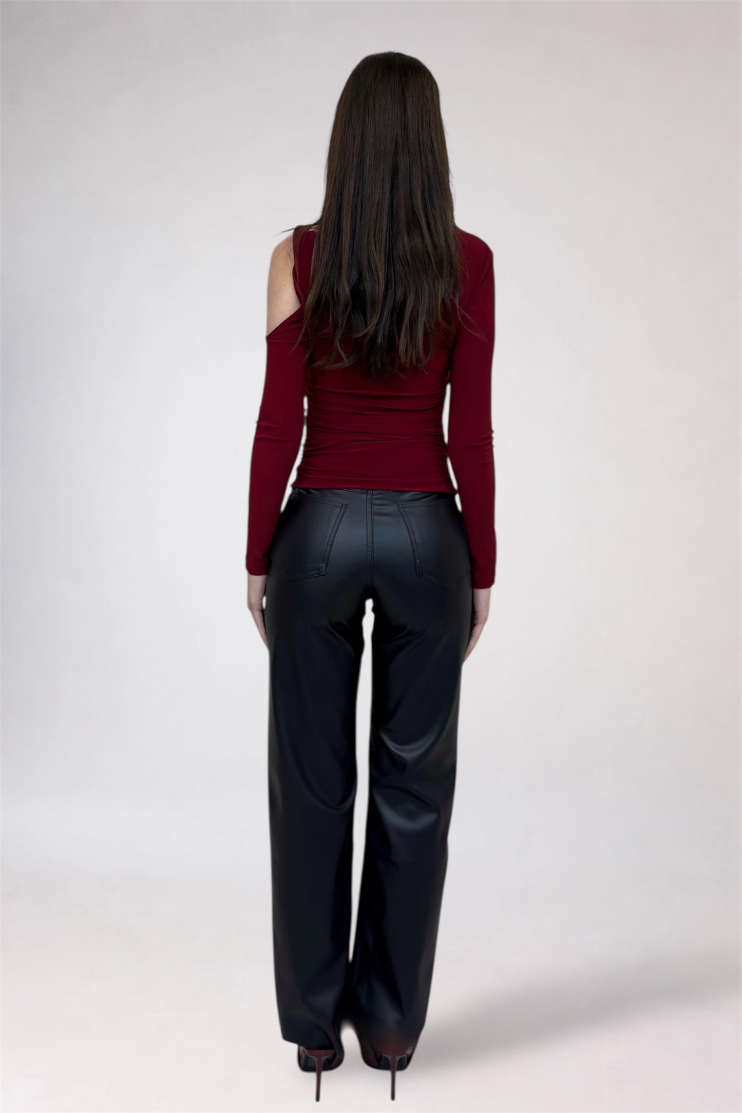 Woman wearing a red top and black pants on a white background