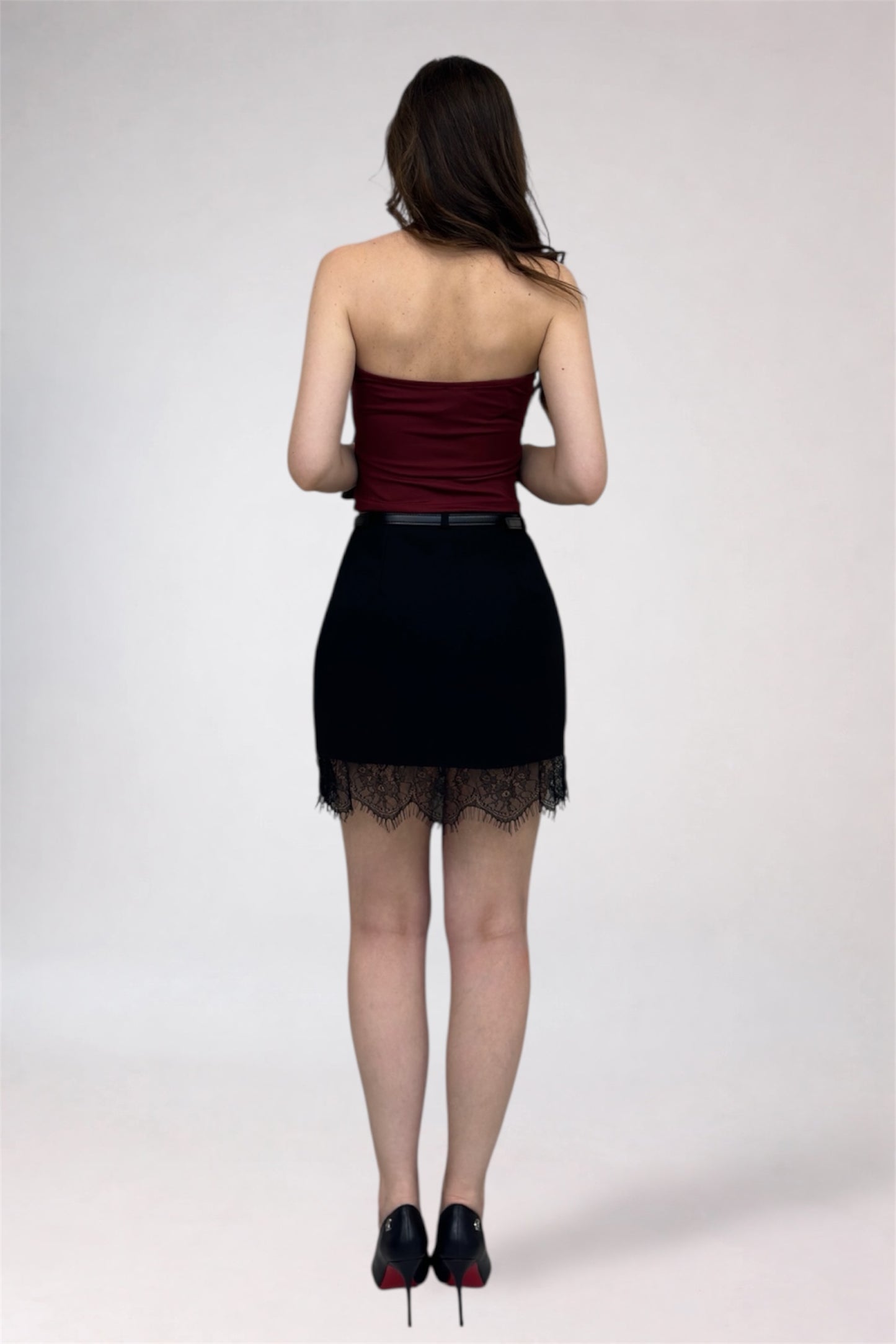 Woman wearing a strapless top and black skirt with lace hem on a white background