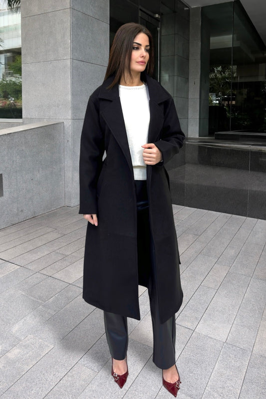 Woman wearing a black coat and white shirt in an urban setting