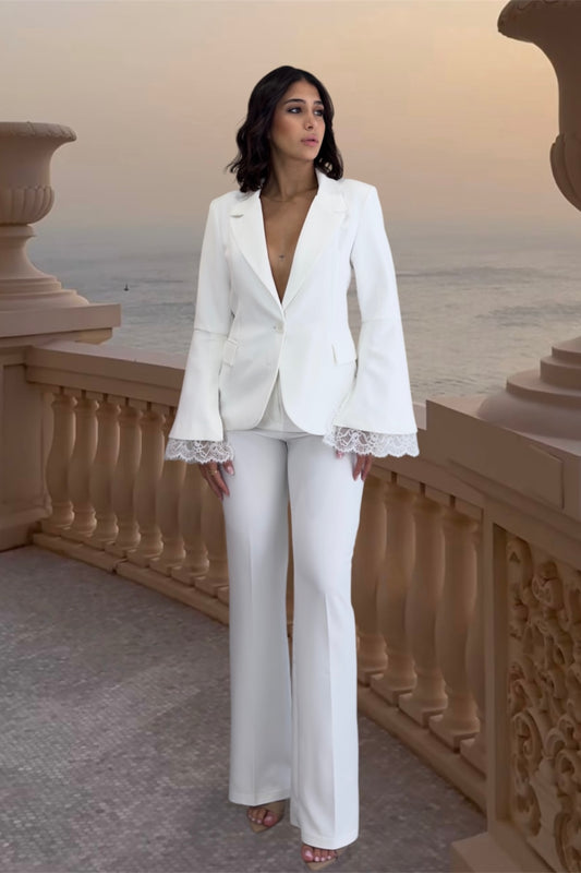 Woman in a white suit standing on a balcony with a scenic background