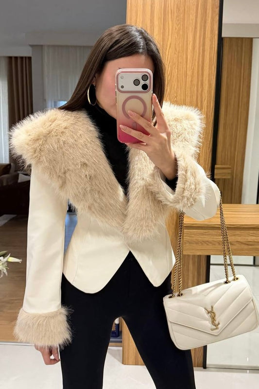 Person wearing a white coat with fur trim, holding a phone and a YSL handbag.