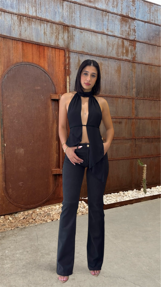 Woman in a black outfit standing in front of a rustic metal wall.