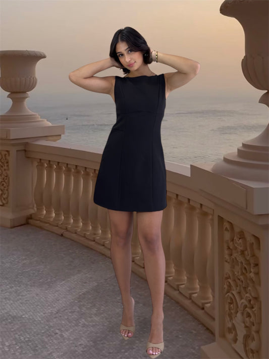 Woman in a black dress standing on a balcony with ocean view