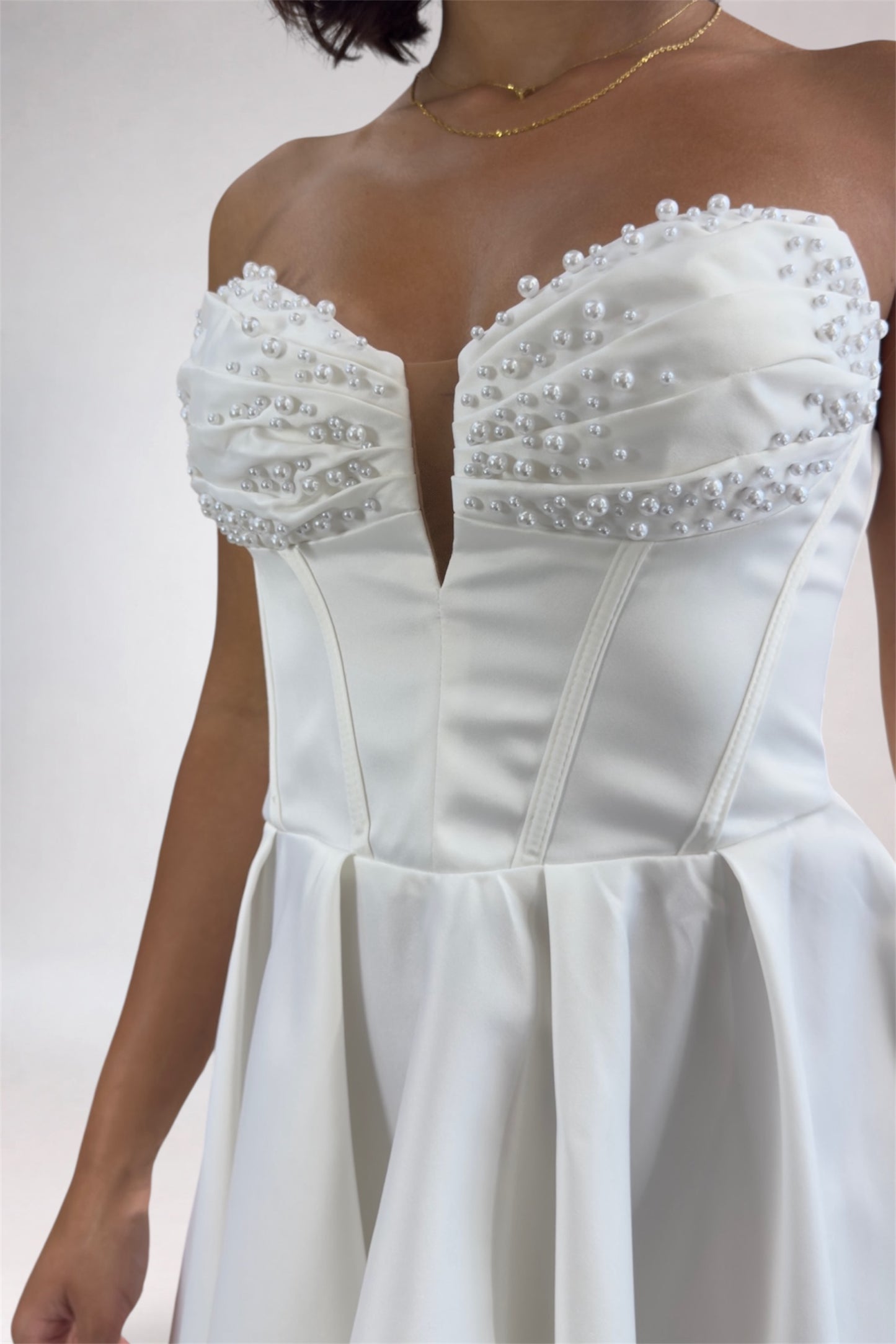 White strapless dress with pearl embellishments on a plain background