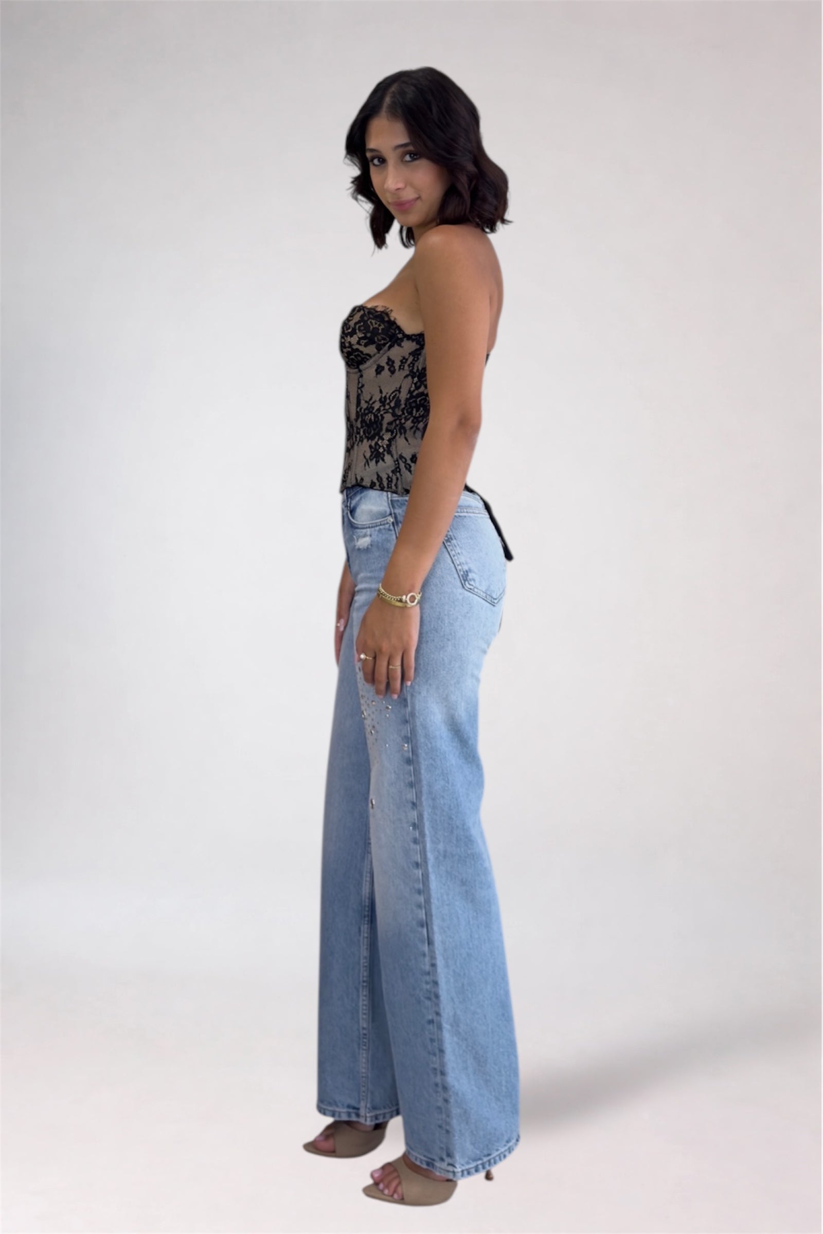 Woman wearing a floral top and light blue jeans on a white background
