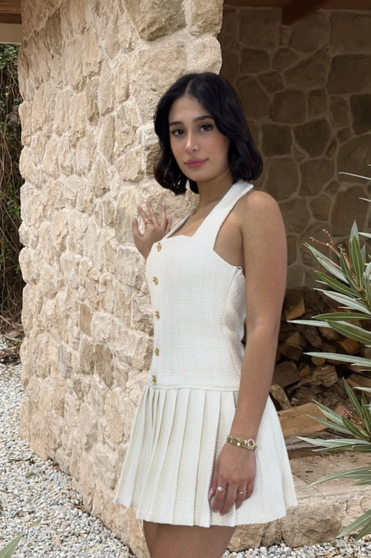Woman in a white dress standing against a stone wall.