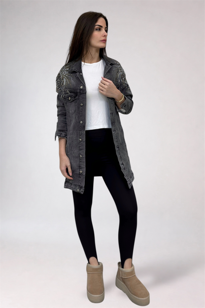 Woman wearing a denim jacket, white shirt, black leggings, and beige boots on a white background