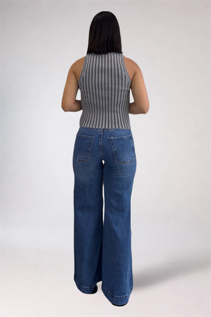 Person wearing a ribbed tank top and blue jeans on a white background